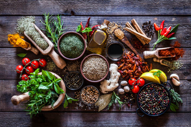 Assorted fresh herbs and dried spices on a wooden table.