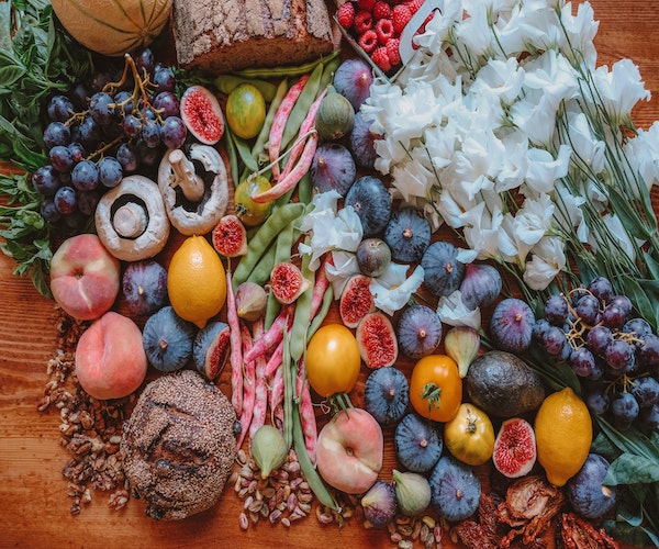 Grocery haul of assorted organic fruits, veggies and flowers on a table. 